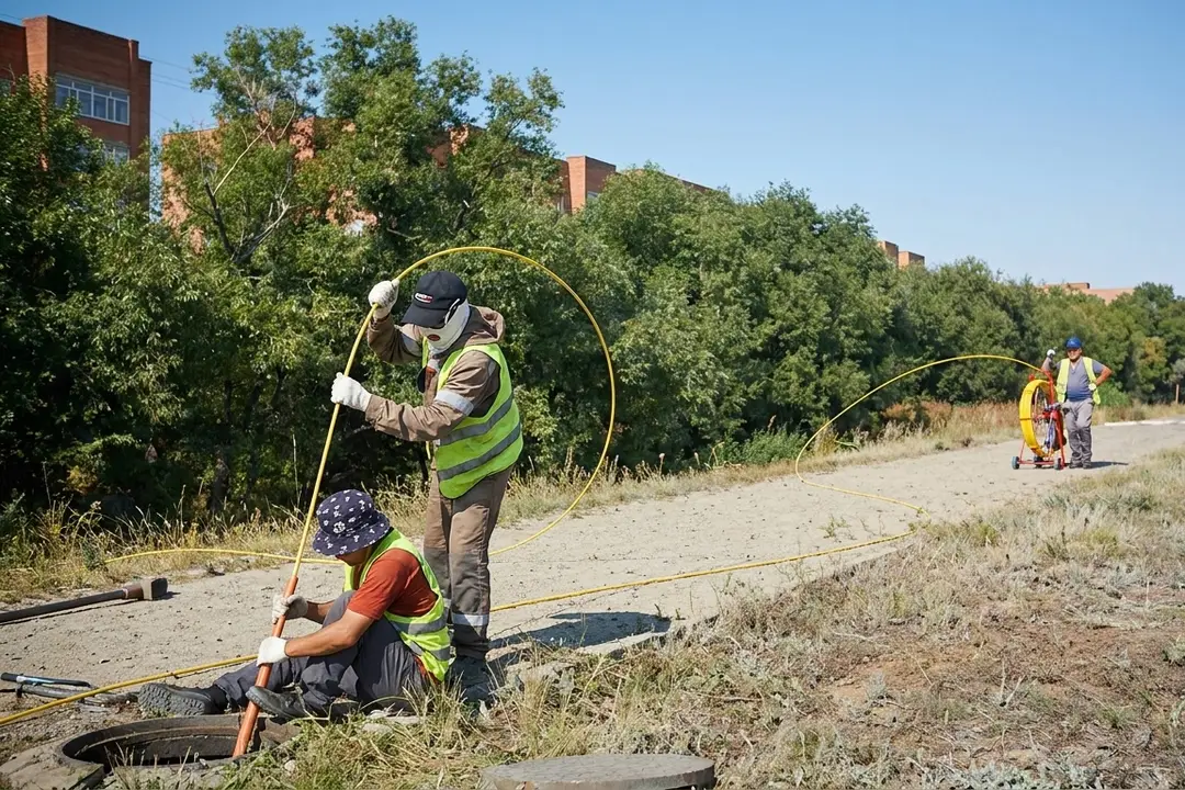 Монтажники протягивают трос в кабельную канализацию GPON на улице жилого массива Уркер